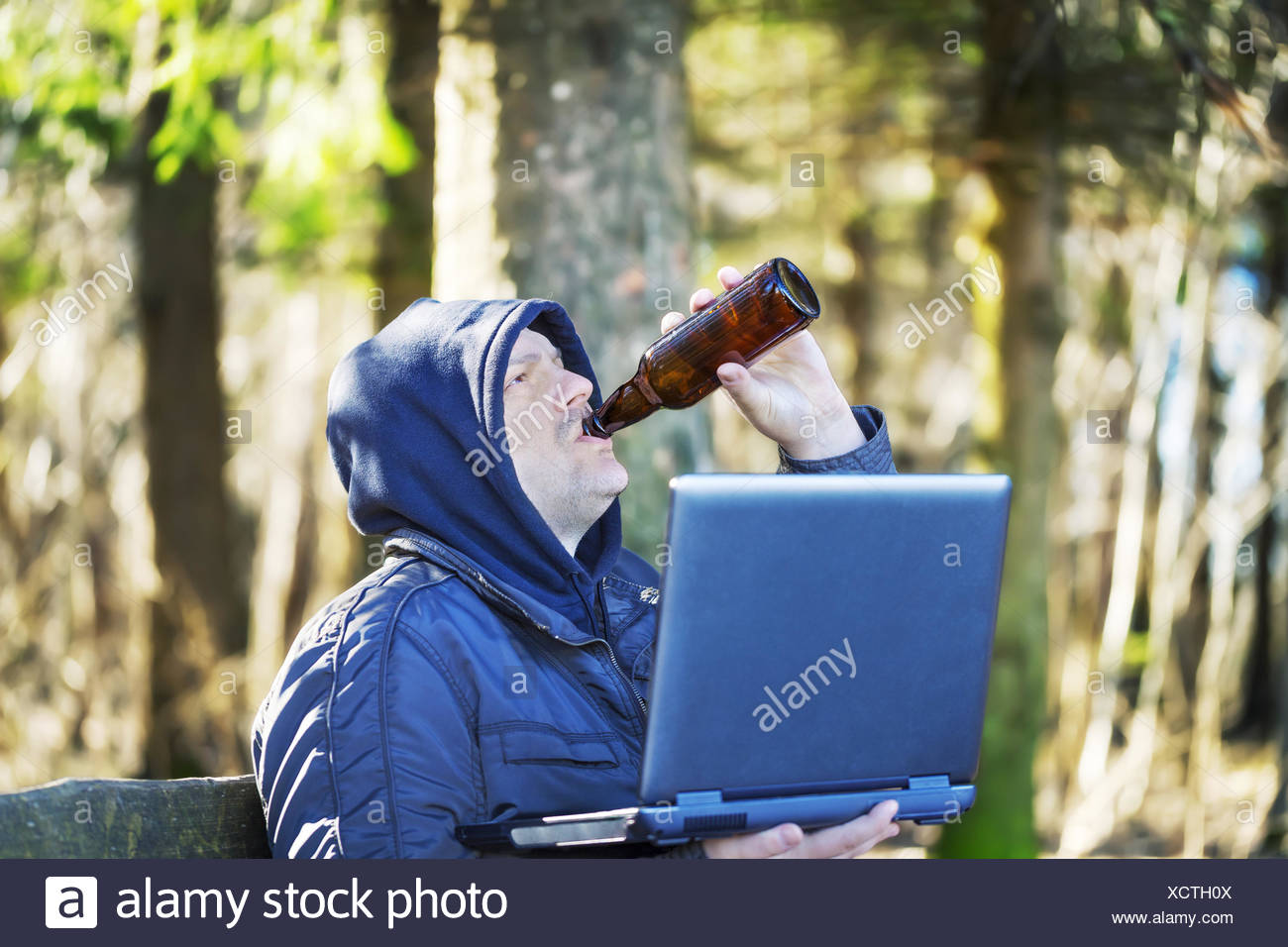man-with-beer-bottle-and-pc-in-the-park-XCTH0X.jpg