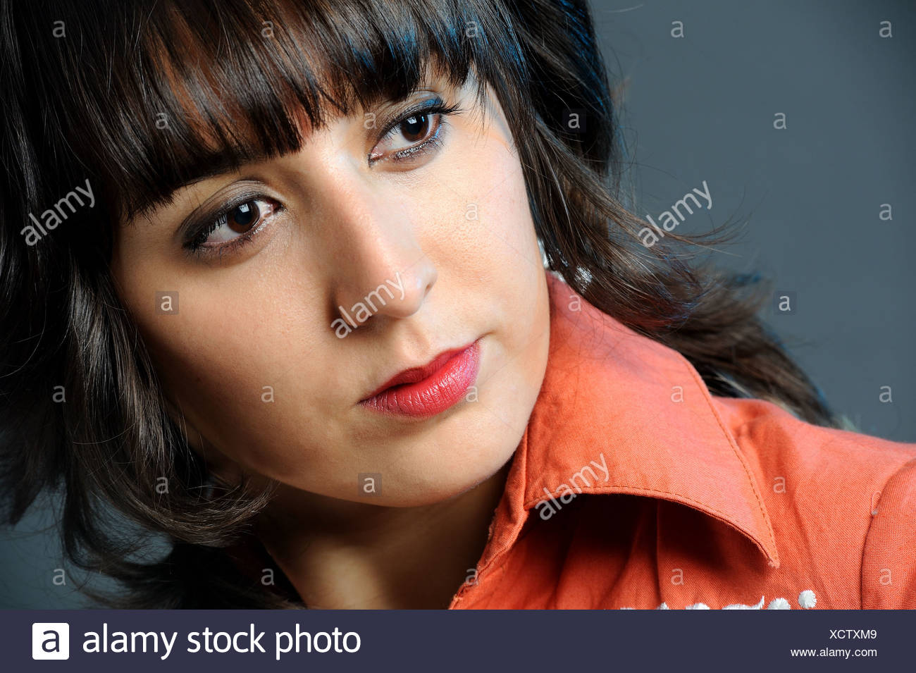 Portrait Of Beautiful Young Woman With Dark Hair Orange Shirt And