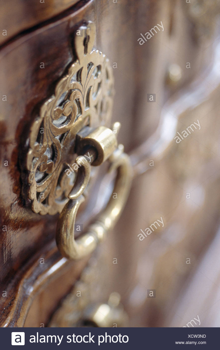 Close Up Of Ornate Brass Handle On Antique Chest Of Drawers Stock