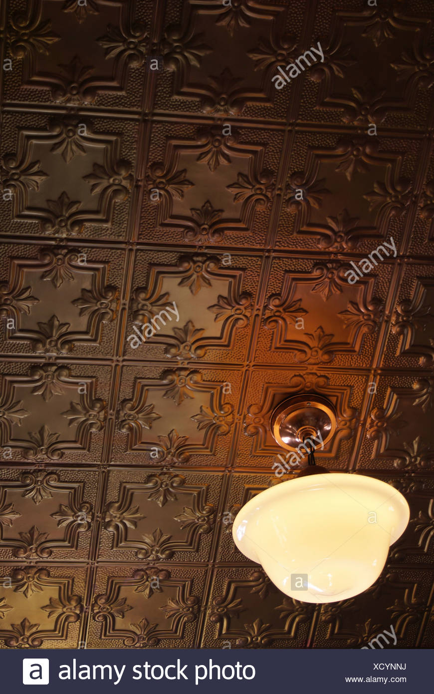 Close Up Of A Ceiling Lamp Suspended From An Antique Tin Ceiling