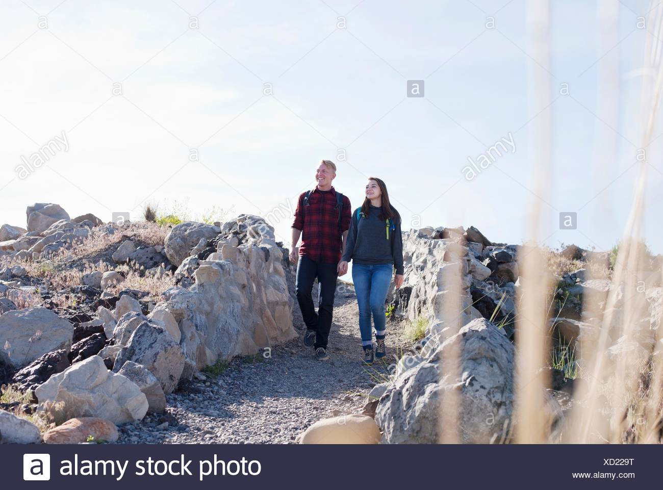 Full length front view of young couple holding hands walking, looking away Stock Photo