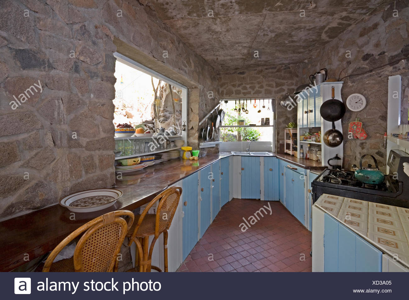 Pale Blue Cupboards In Rustic Caribbean Kitchen With Stone Walls