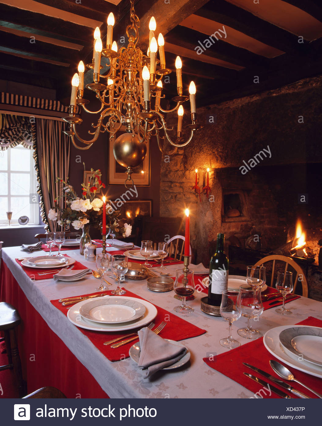 Traditional Country House Diningroom With Lit Chandelier Above Table Settings On Red Mats Stock Photo Alamy