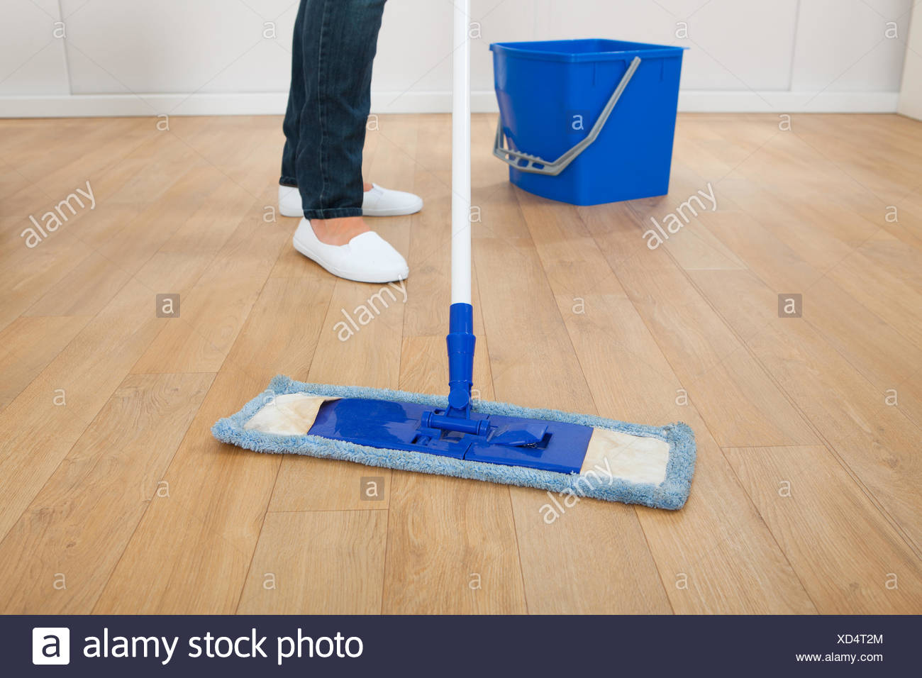 Low Section Of Young Woman Mopping Hardwood Floor At Home Stock