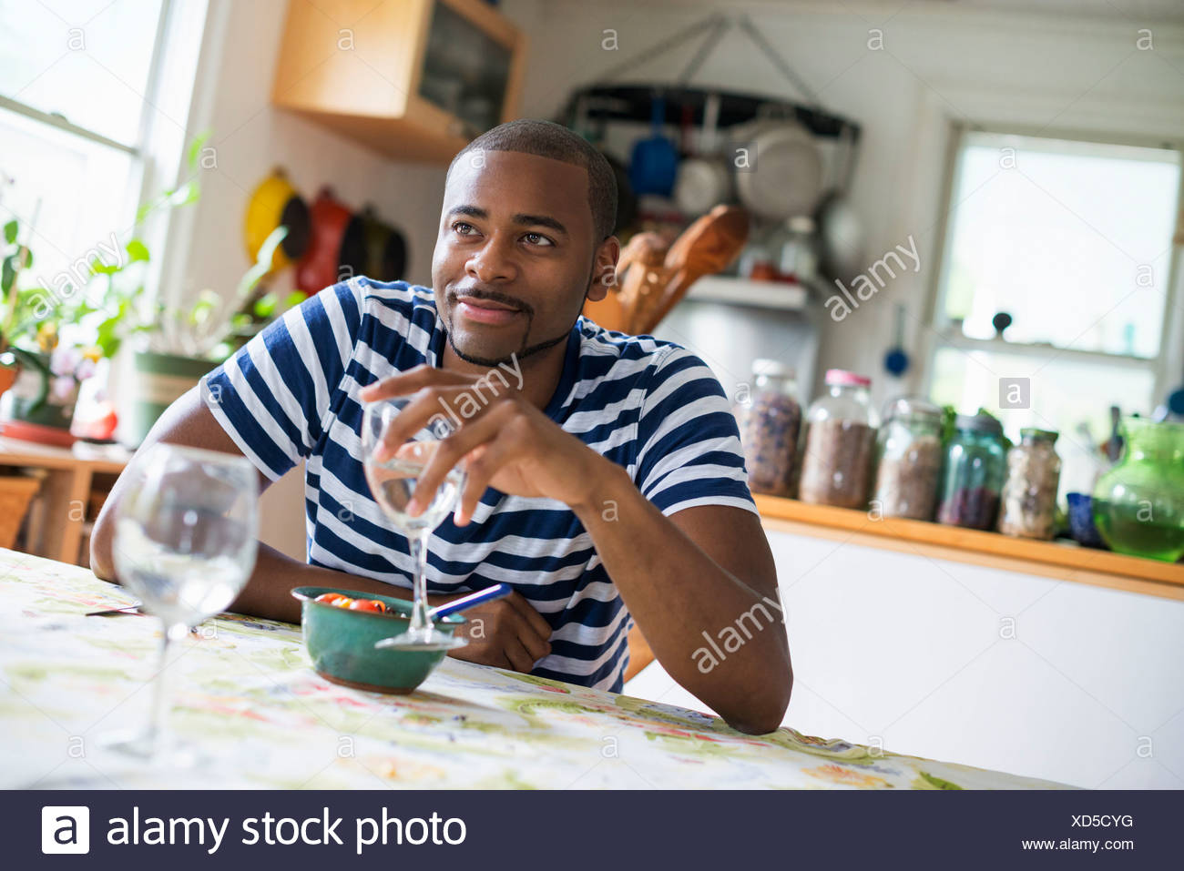 A man sitting at a table eating dessert, holding a glass of wine. Stock Photo