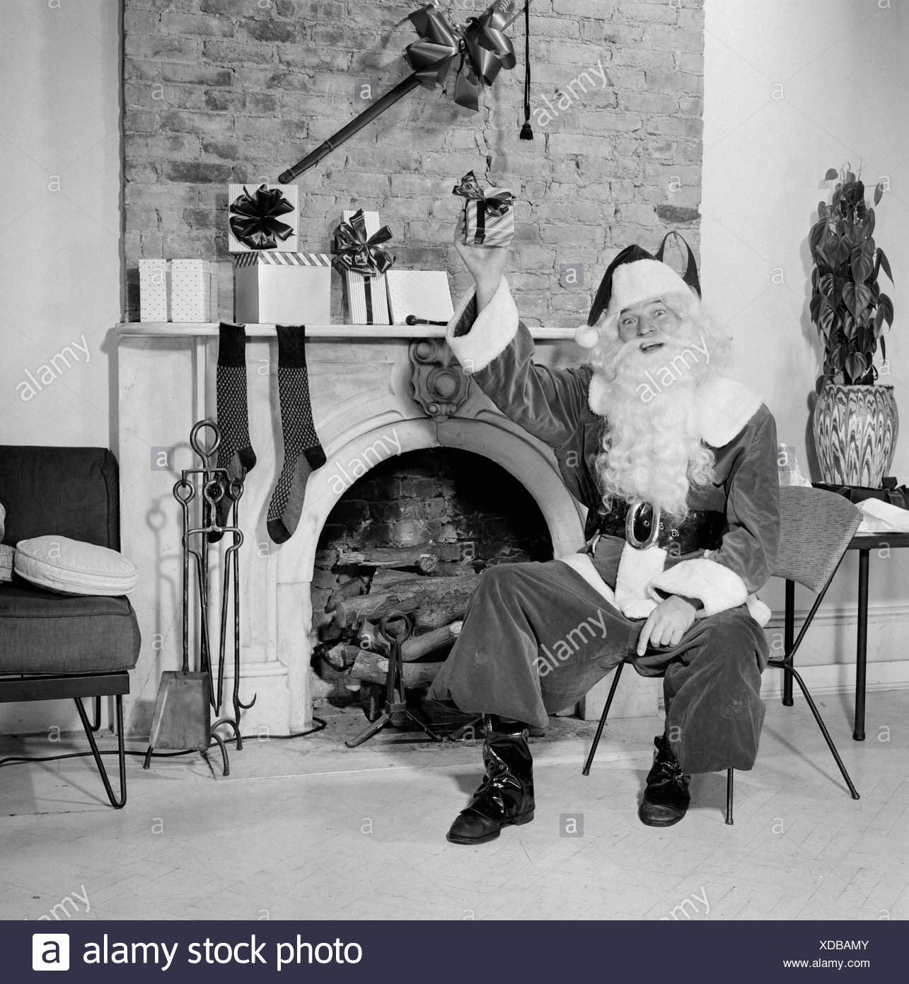 Portrait Of Santa Claus Sitting In Front Of A Fireplace And