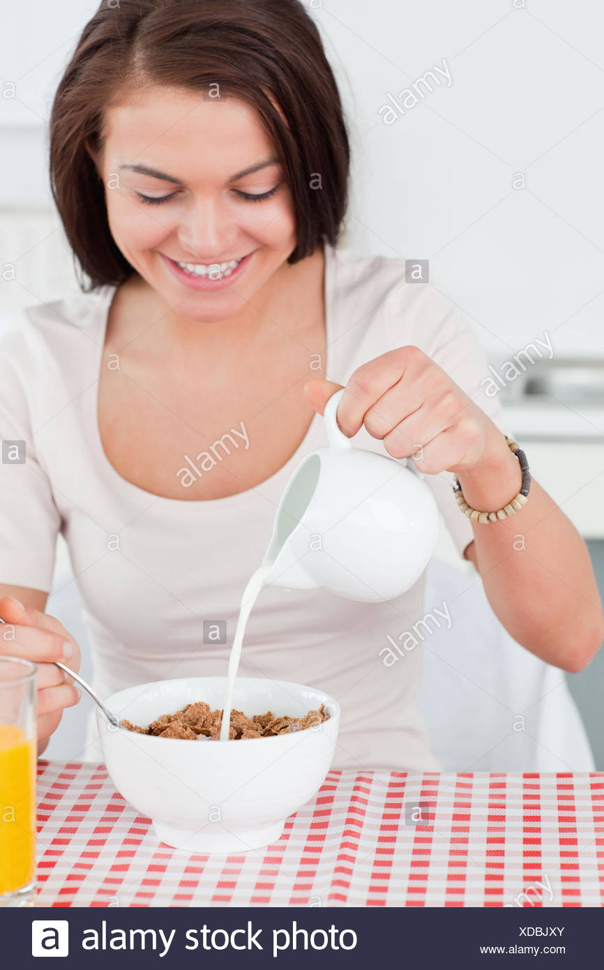 Beautiful Dark Haired Woman Pouring Milk In Her Cereal Stock Photo