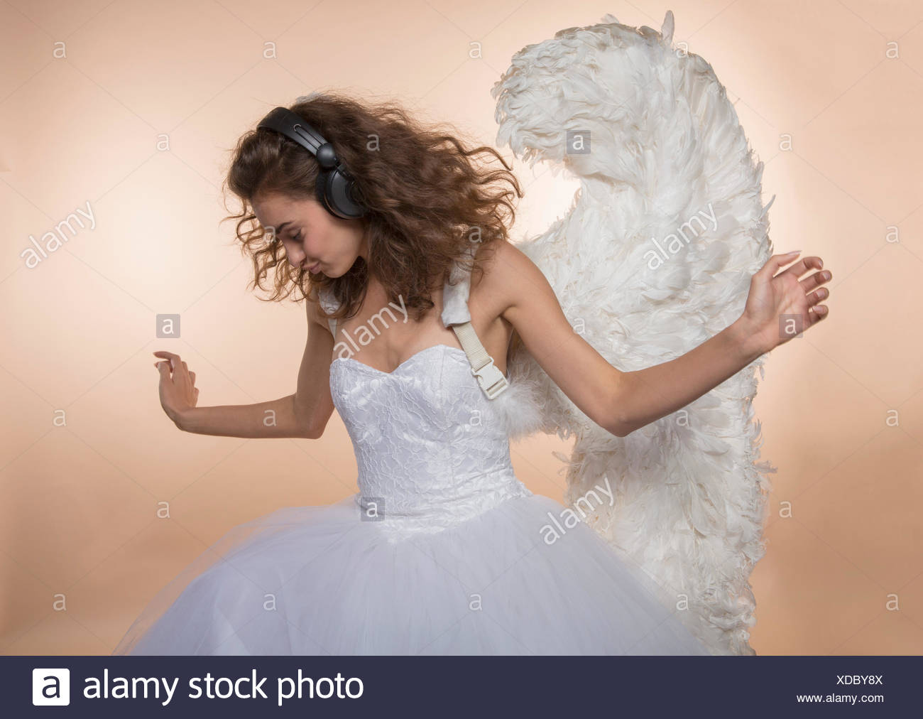 Bride In Angel Wings Dancing While Listening Music Against Colored Background Stock Photo Alamy