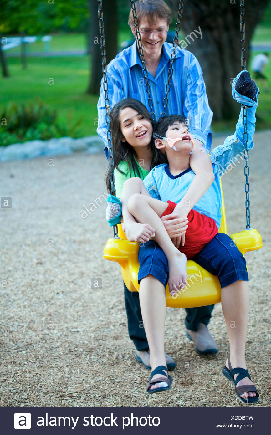 Big Sister Holding Disabled Brother On Special Needs Swing