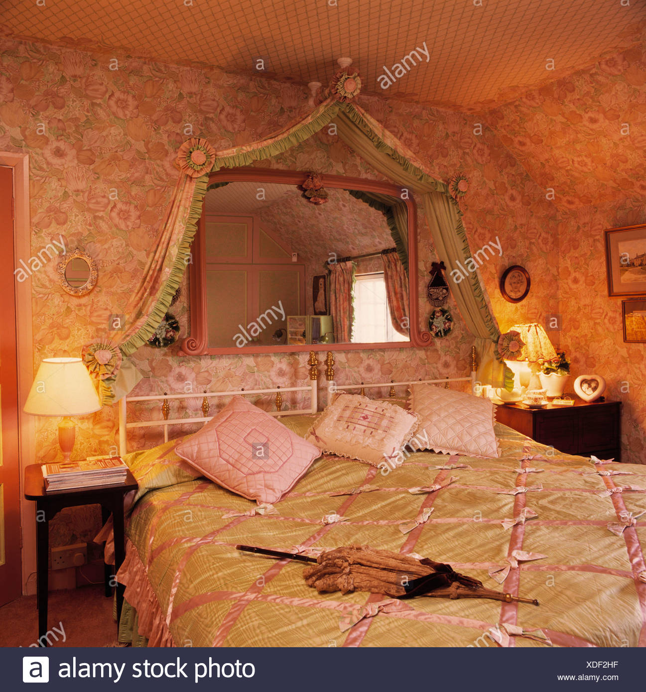 Mirror Above Bed With Pink And Green Satin Quilt In Bedroom