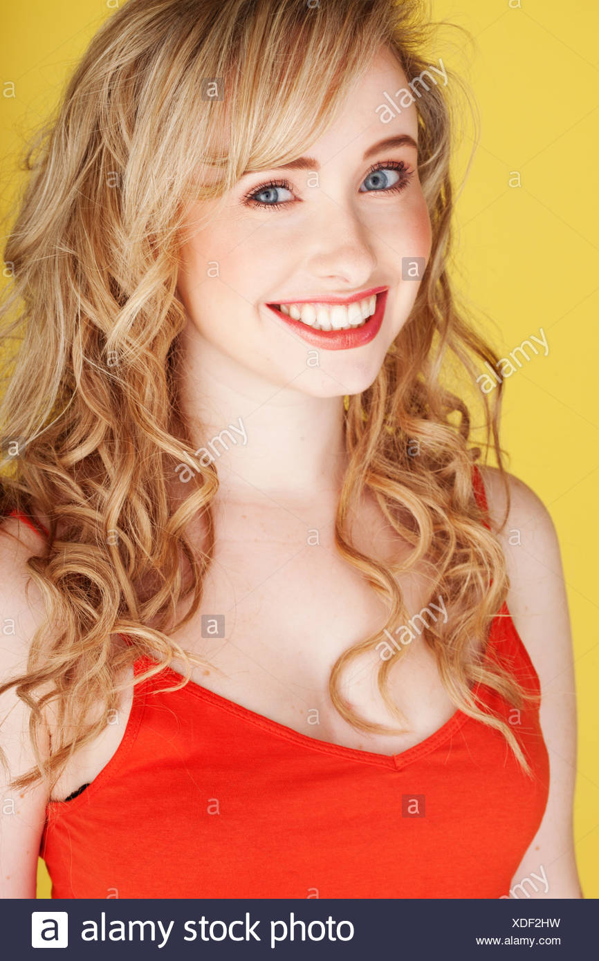 Smiling Teenage Girl With Long Blonde Curly Hair Wearing A Red