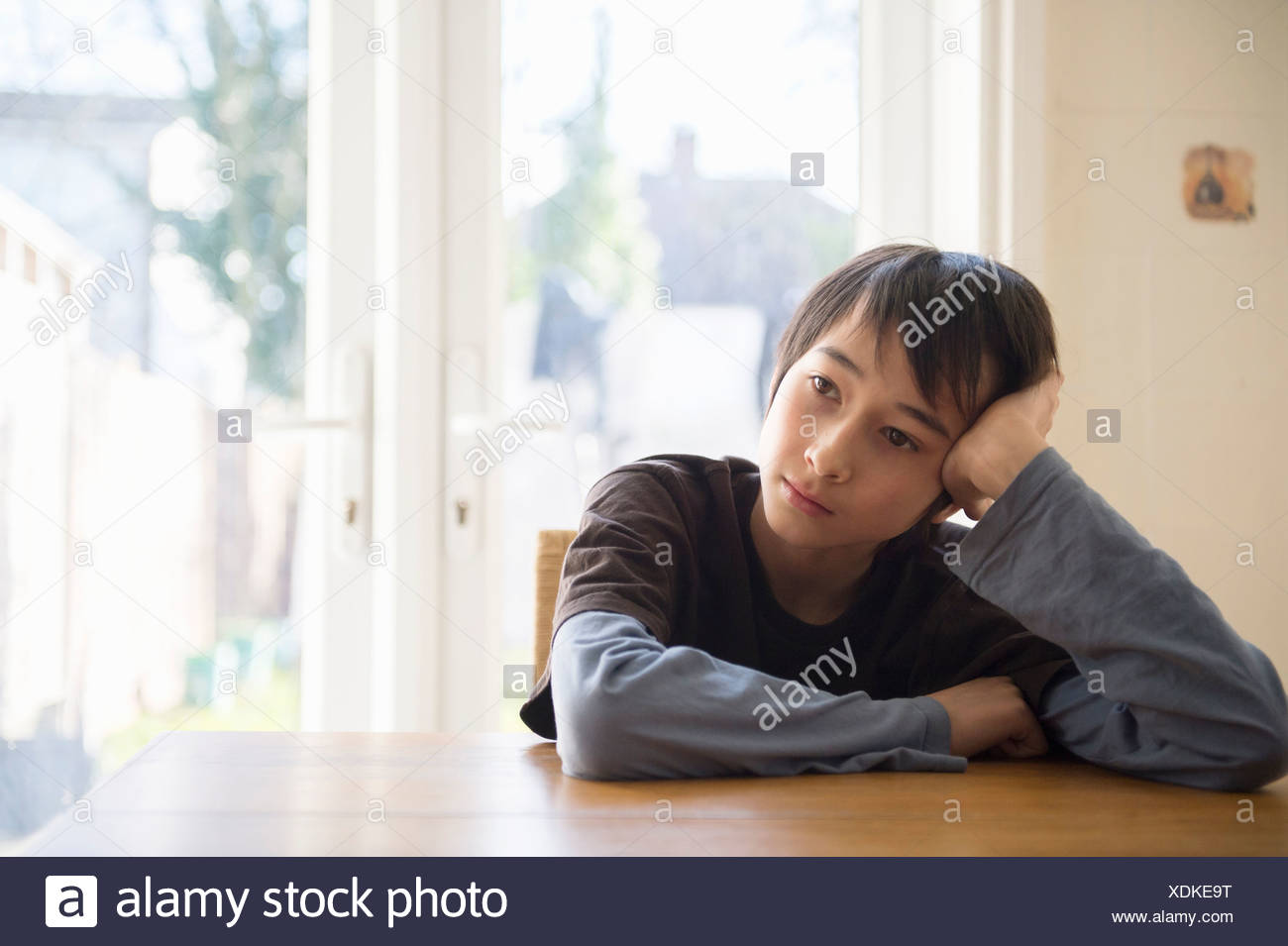 Boy Sitting At Table Head Resting In Hand Stock Photo 283784756