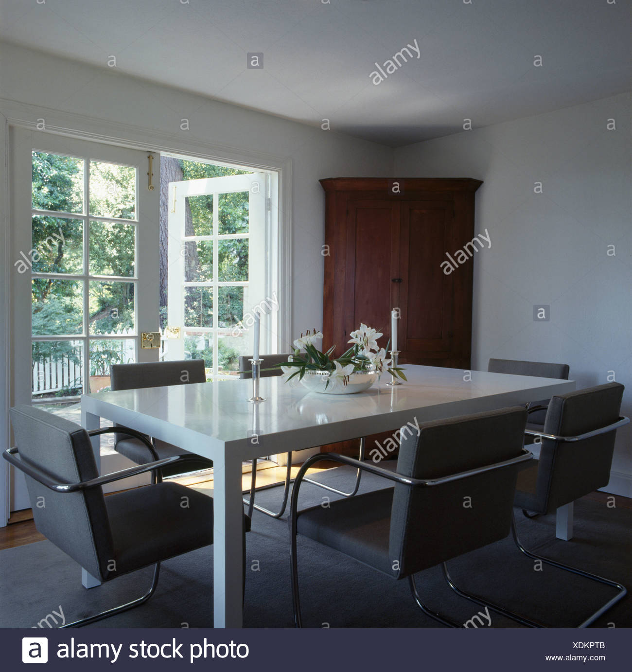 Grey Upholstered Chairs And White Table In Modern White Dining Room With French Windows Stock Photo Alamy