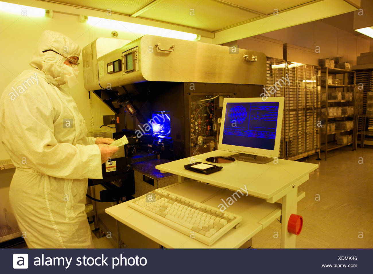 Engineer In Clean Suit Examining Silicon Wafer At Computer