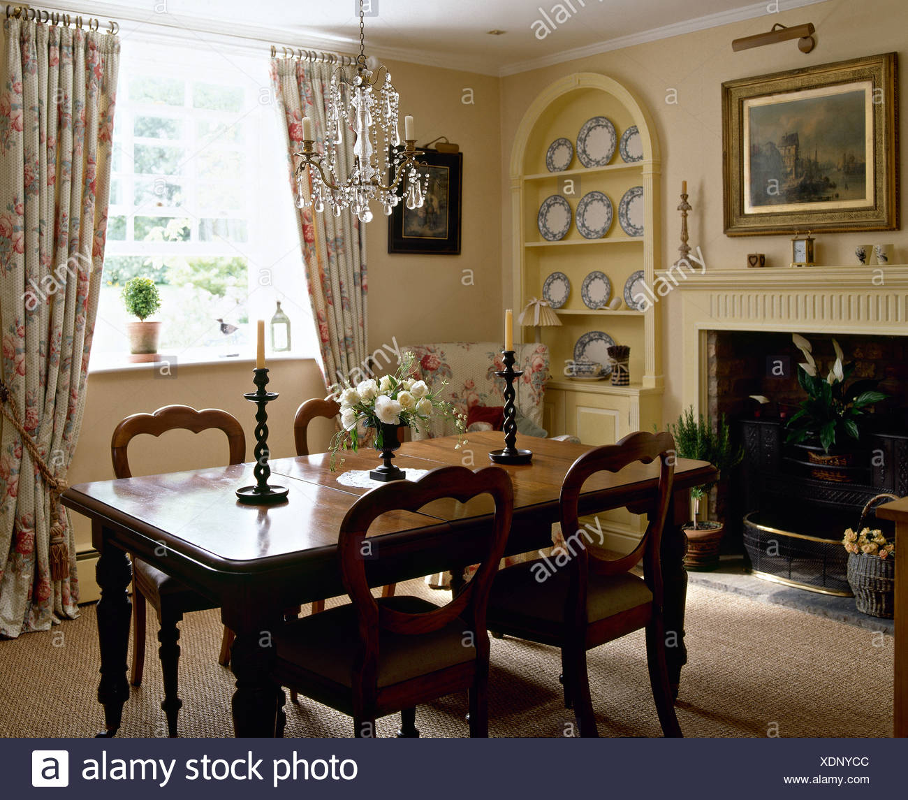 Antique table and balloon back chairs in traditional living room with  alcove shelving and floral curtains Stock Photo - Alamy