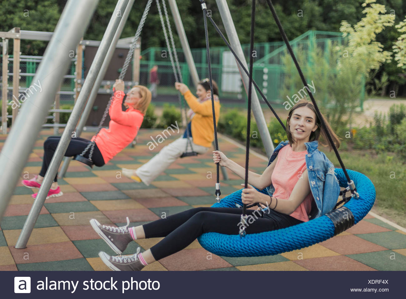 Full Length Of Happy Women Swinging On Swing At Playground