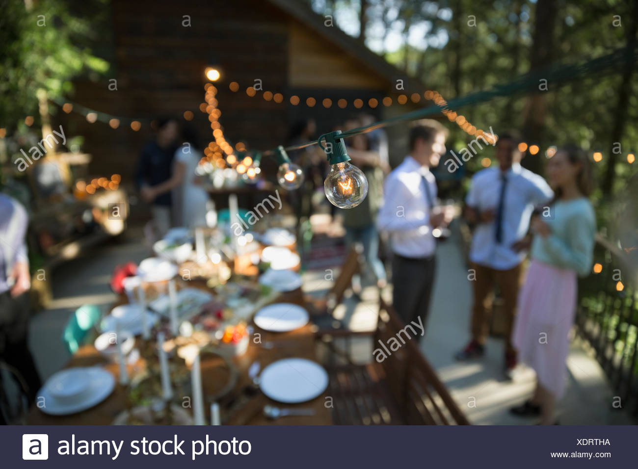 String Lights Hanging Over Long Table On Balcony At Wedding