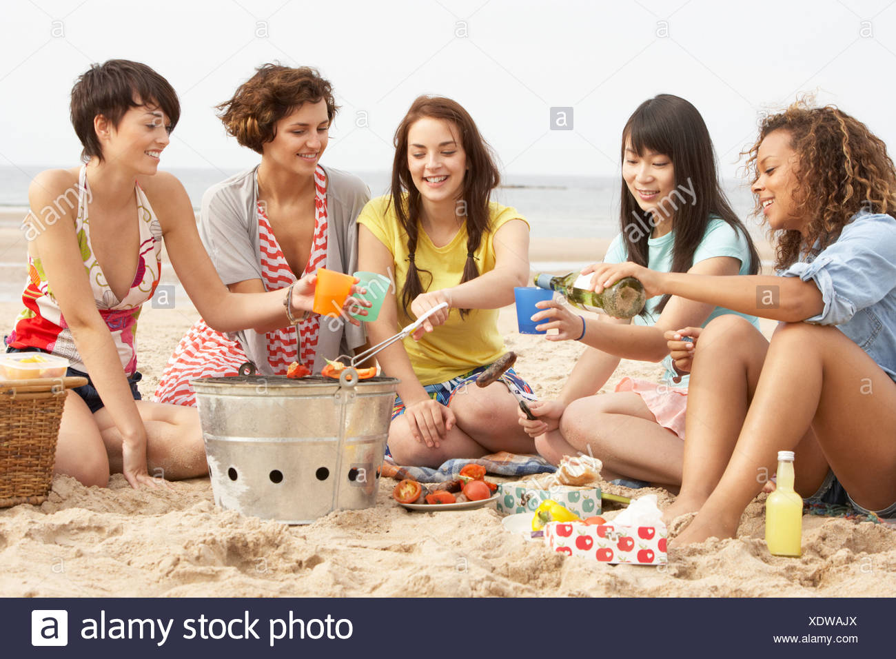 group-of-girls-enjoying-barbeque-on-beach-together-XDWAJX.jpg