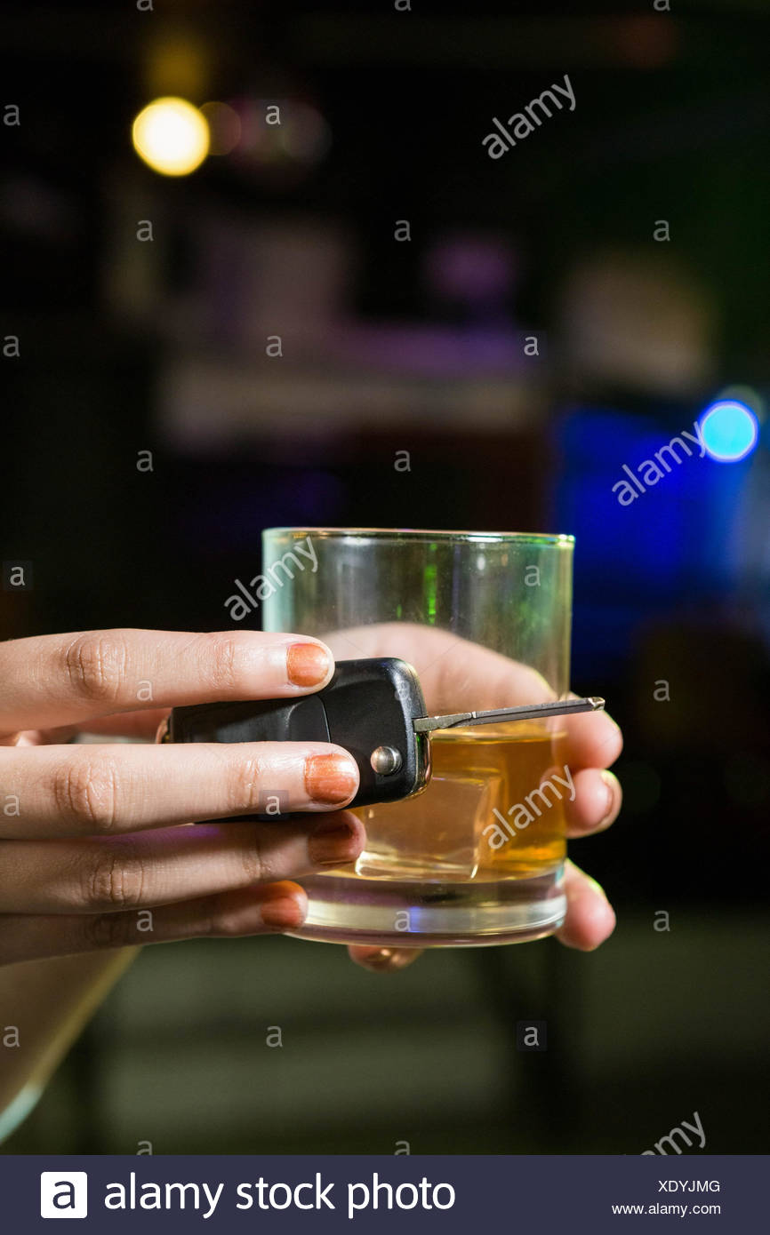 Woman holding a glass of whiskey and car keys Stock Photo