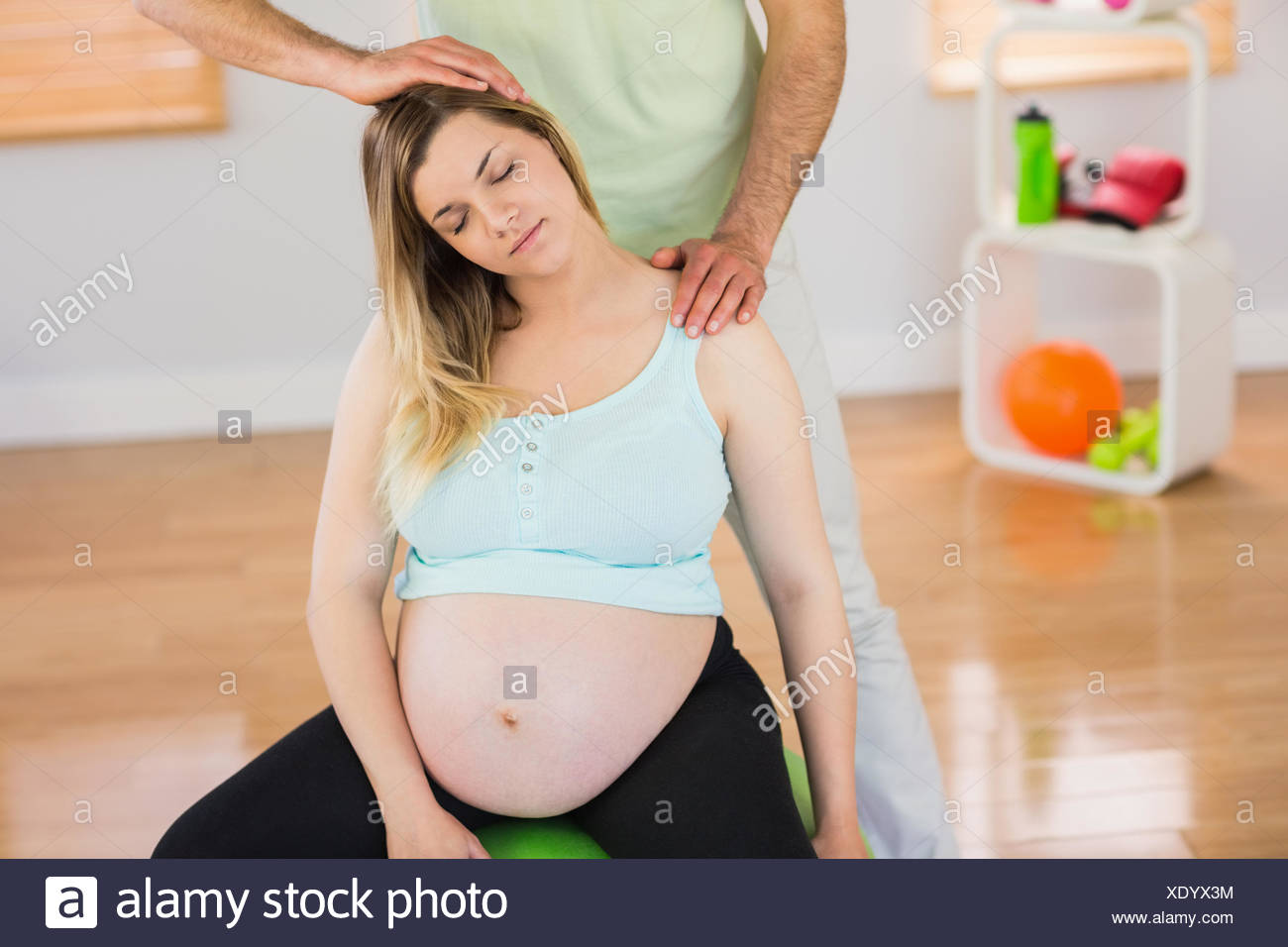 Pregnant Woman Having Relaxing Massage While Sitting On Exercise
