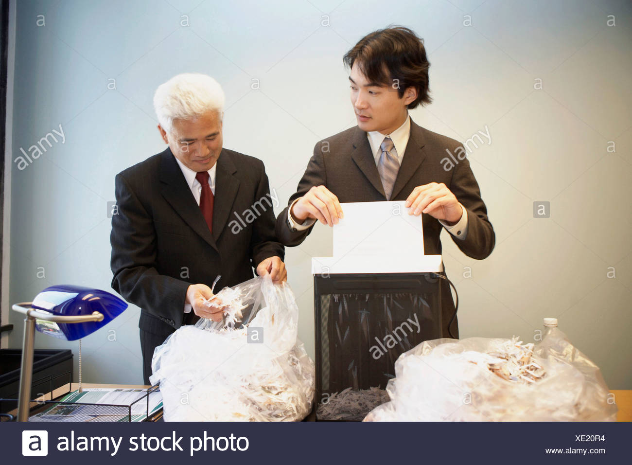 Businessman Shredding A Sheet Of Paper With Another Business Man