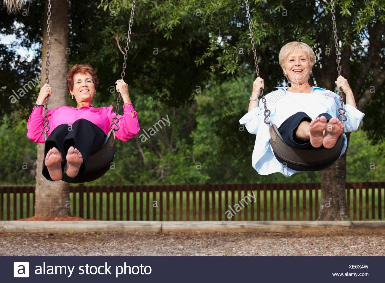 Two Women Swinging On Swings Side By Side Stock Photo