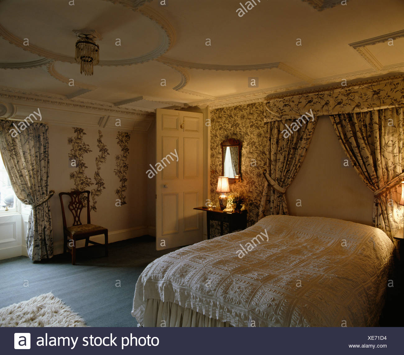 Bed With Drapes And Floral Linen In Country Bedroom With