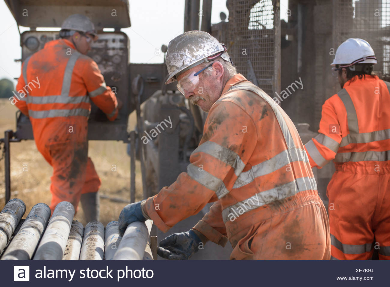 Workers in hard hats operating drilling rig Stock Photo
