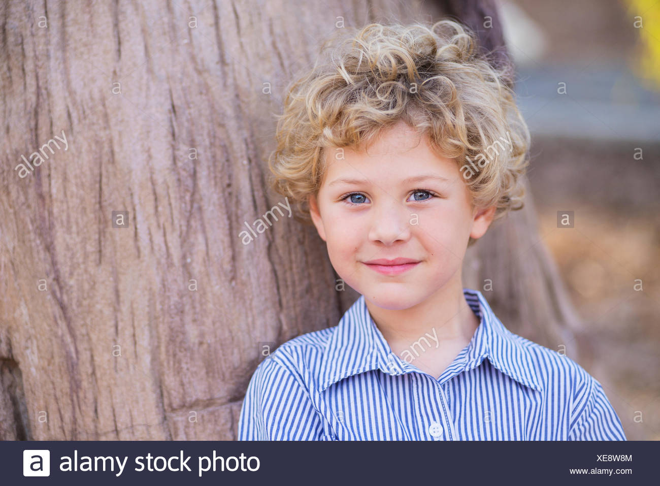 Portrait Of A Young Boy With Blond Curly Hair And Blue Eyes