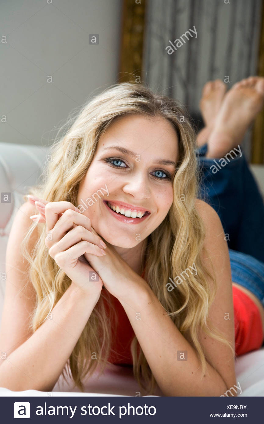 Female Long Blonde Wavy Hair Wearing Orange Tank Top And Blue