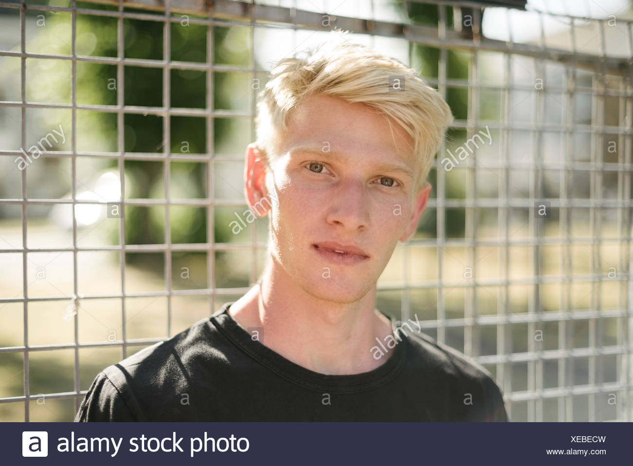 Portrait Of Blond Haired Young Man By Wire Fence Stock Photo