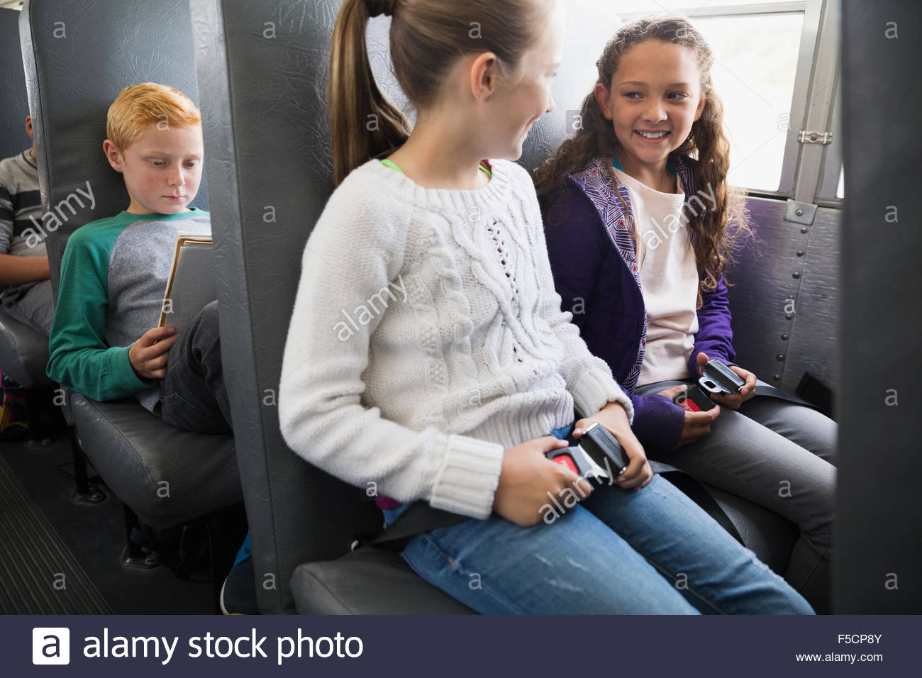 Schoolgirls fastening seat belts on school bus Stock Photo 89406043.