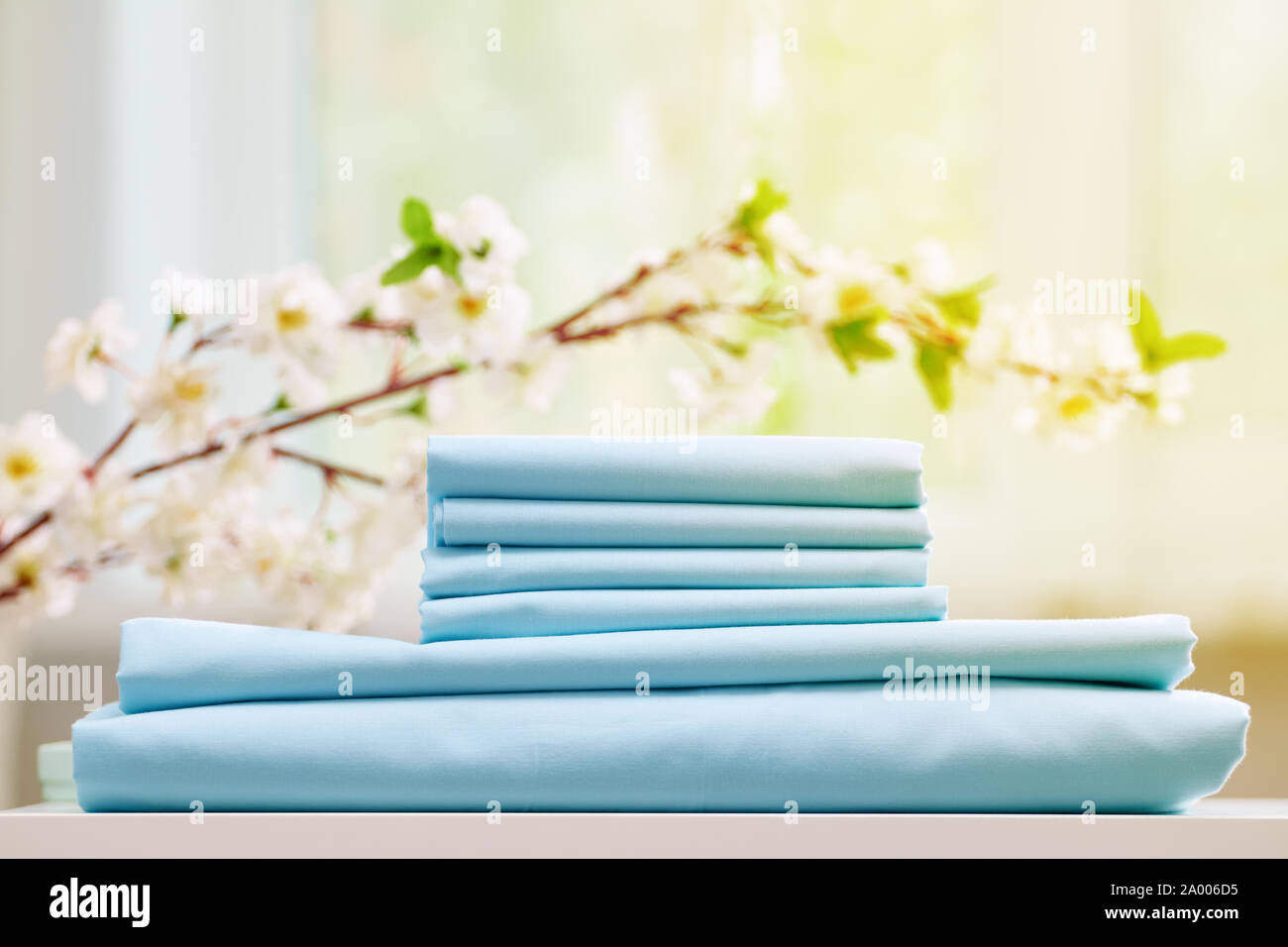 Blau Bettwäsche auf der Kommode. Unscharfer Hintergrund. Blühenden Zweig. Stockfoto