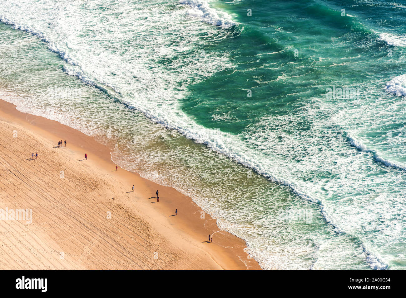 Luftbild von oben auf das Meer, auf das Meer Strand und Wasser Wellen mit Menschen auf Sand Ufer mit Schwerpunkt auf der Skala der Menschen und der Natur. Surfers Paradise Stockfoto