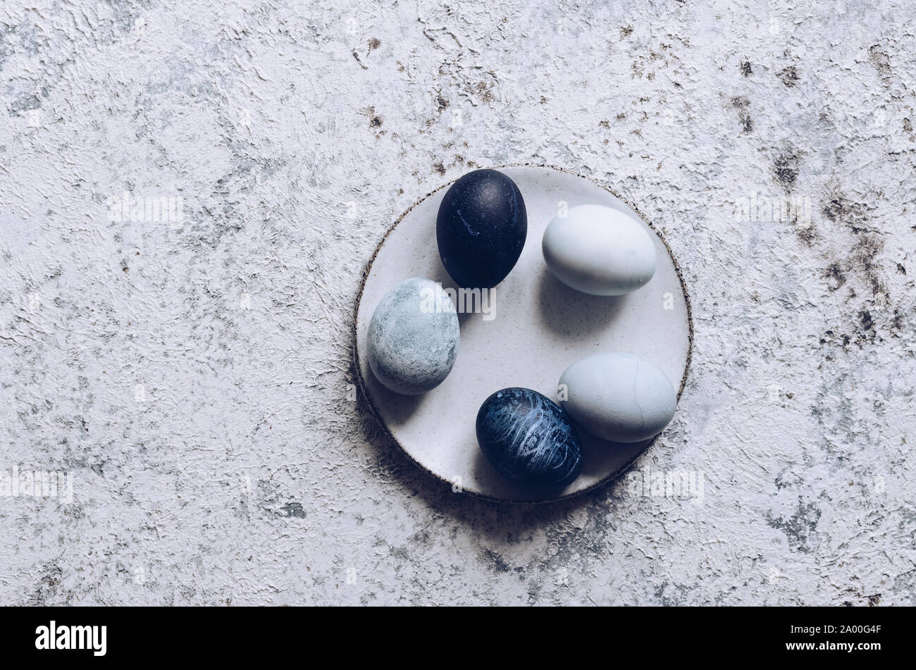 Ostereier mit Marmor Stein Effekt mit natürlichen Farbstoff carcade Blume auf grauem Beton Hintergrund gemalt. Stockfoto