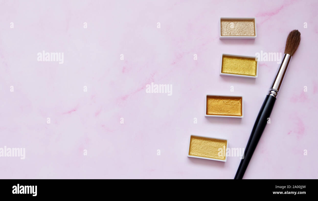 Pinsel und goldene Farbe Paletten, mit rosa Hintergrund. Stockfoto