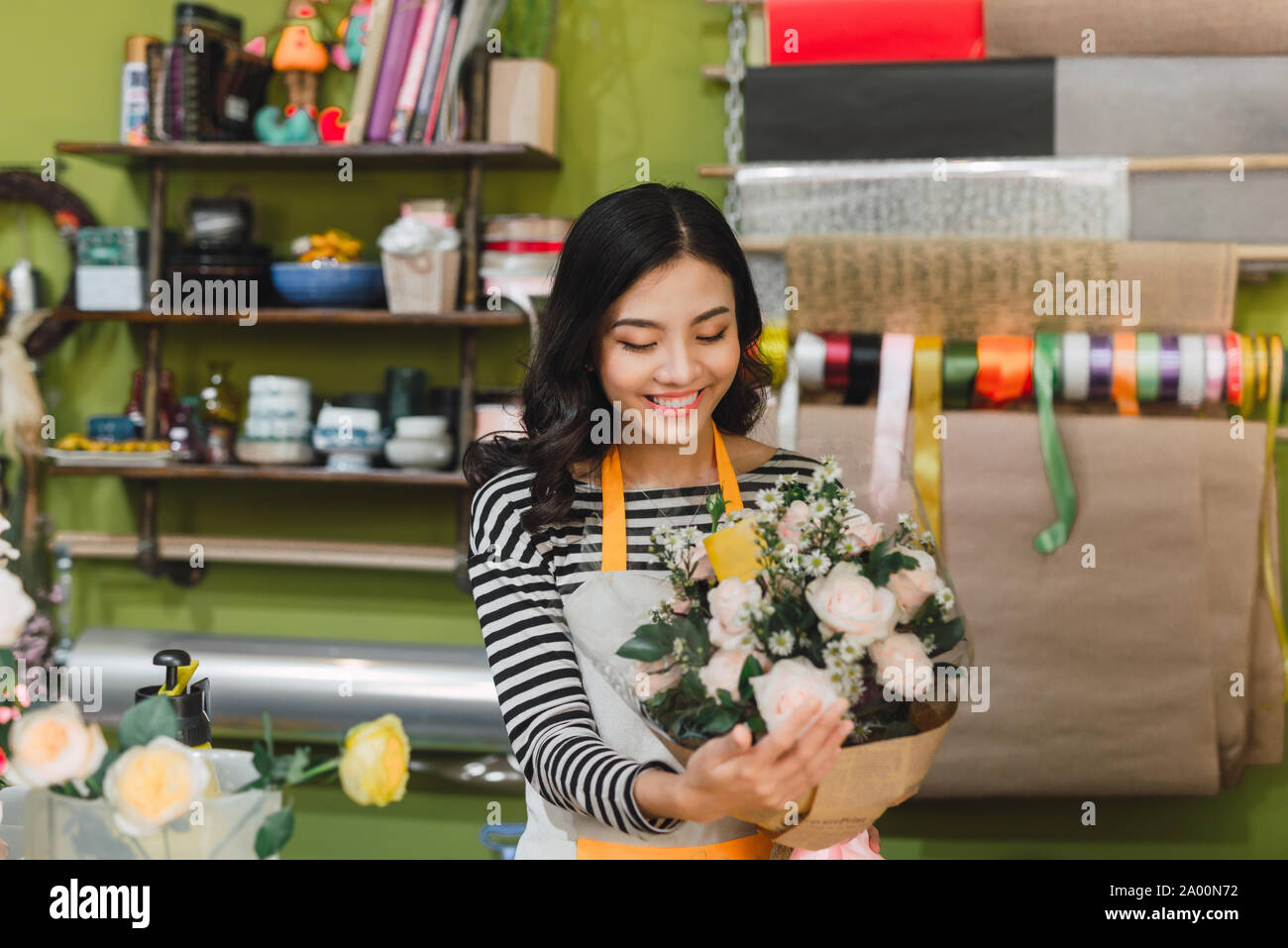Lächelnde Frau Florist, Small Business Flower Shop Besitzer, an der Theke, freundlich in die Kamera zu einem besonderen Blumengruß arbeiten. Stockfoto