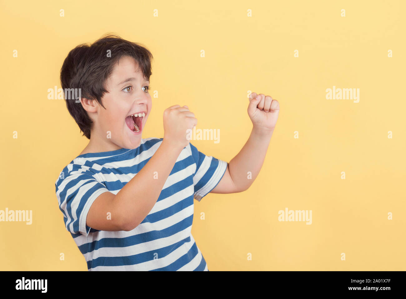 Lustig Kind mit den Händen in der Luft schreien auf gelbem Hintergrund Stockfoto