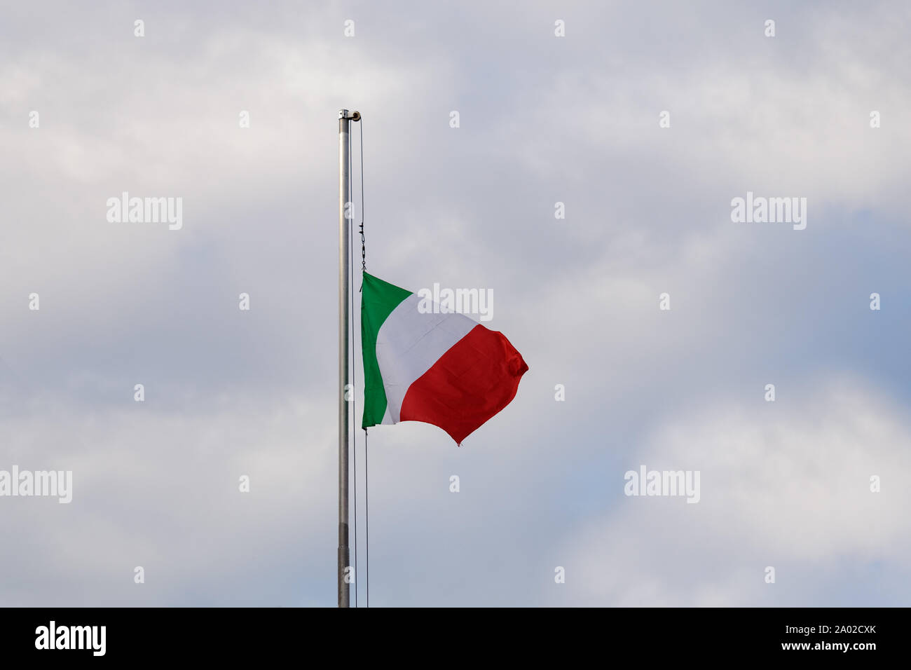 Italienische Trikolore am halben Mast gegen einen bewölkten Himmel Stockfoto
