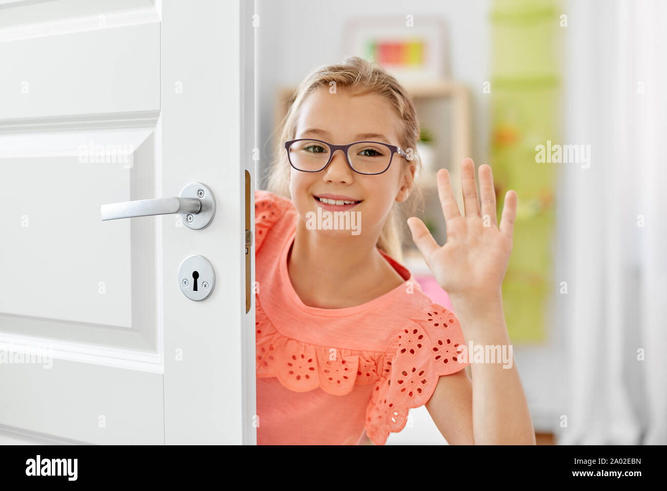 glücklich lächelnd schönes Mädchen hinter Tür zu Hause Stockfoto