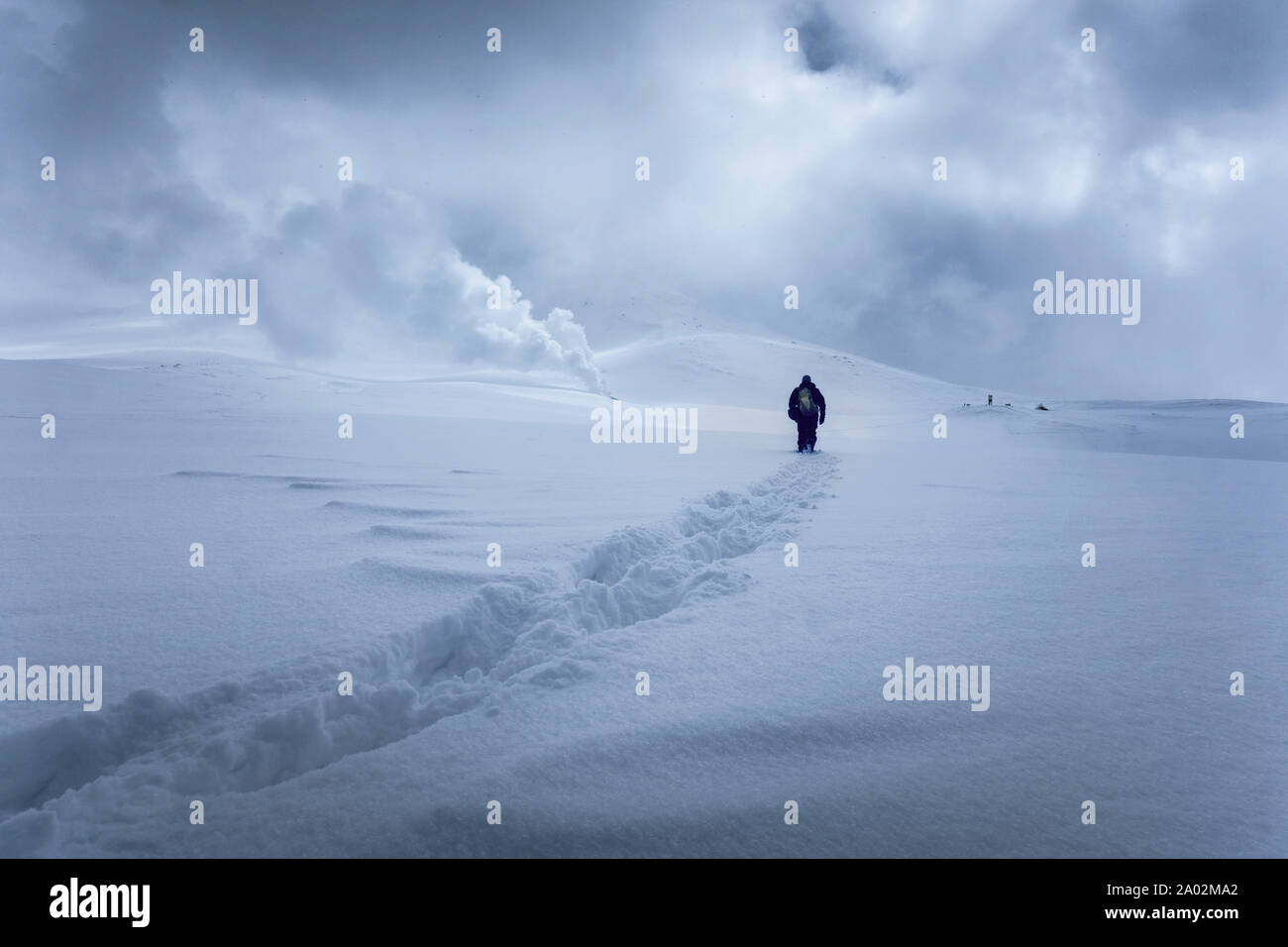 Mann, der durch den tiefen Schnee zu den Dampffumarolen auf dem Berg Asahi, Hokkaido, Japan, geht Stockfoto