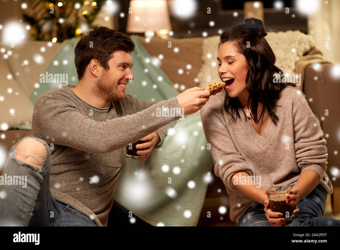 Glückliches Paar essen Waffeln mit Kakao zu Hause Stockfoto