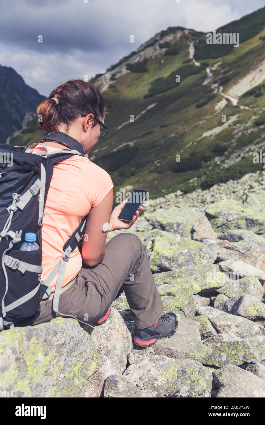 Das aktive Leben der Diabetiker, sitzt Frau am Handy mit überprüften Blutzuckerspiegel von entfernten neue Technologie Sensor auf ihre Hand montiert auf der Suche Stockfoto