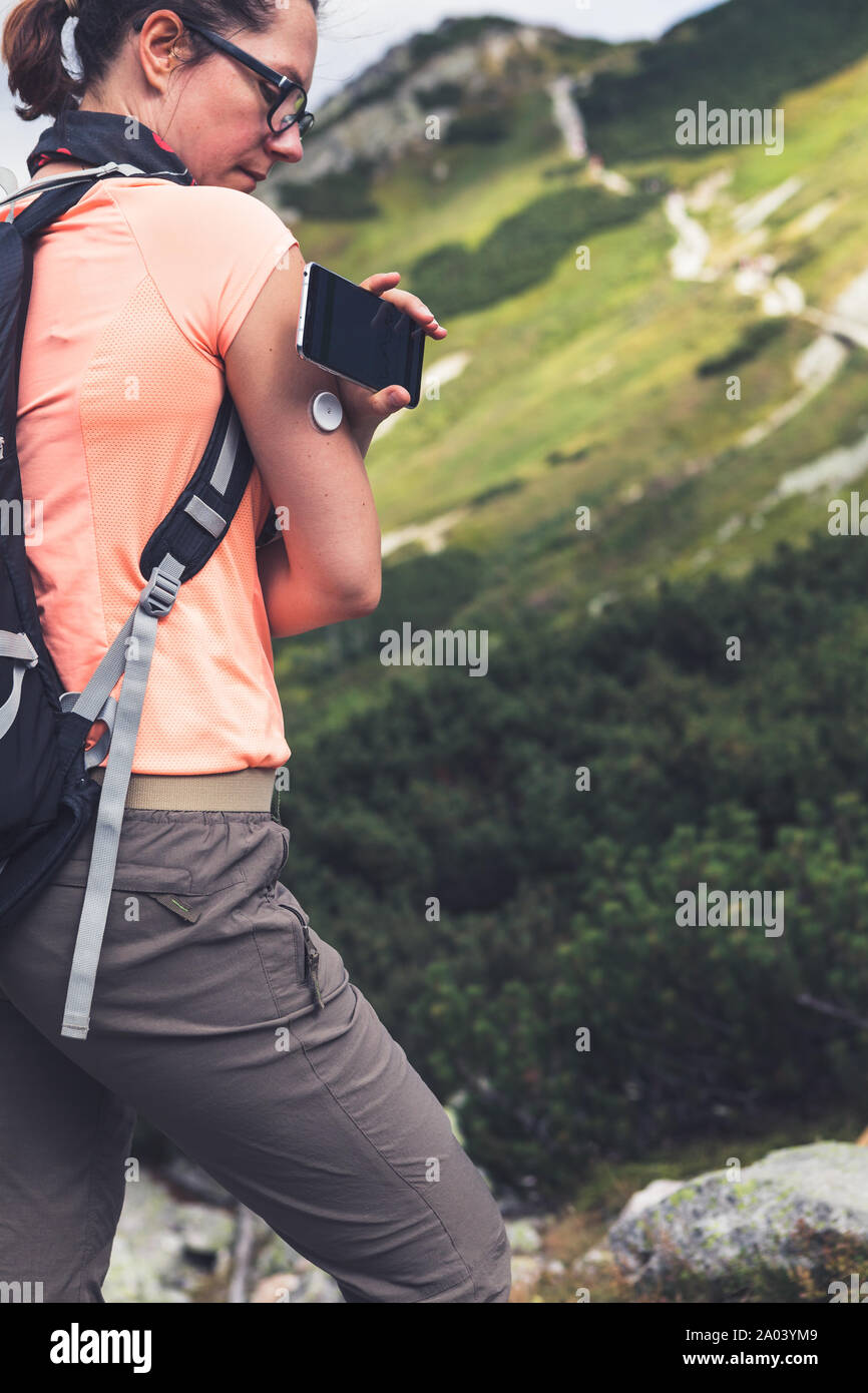 Das aktive Leben der Diabetiker, Frau wandern und Kontrolle der Blutzuckerspiegel mit einer Fernbedienung neue Technologie sensor und Handy ohne Blut Stockfoto