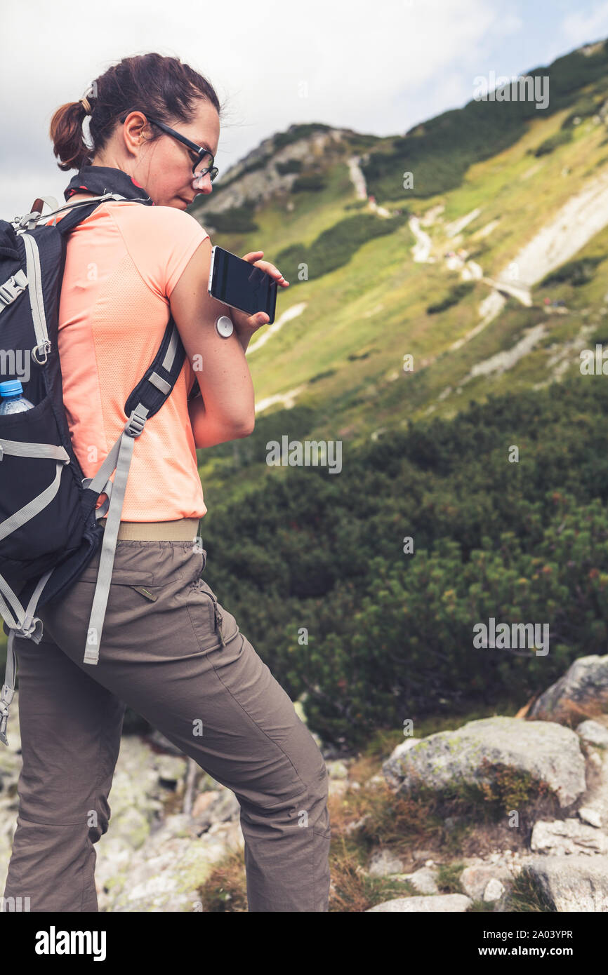 Das aktive Leben der Diabetiker, Frau wandern und Kontrolle der Blutzuckerspiegel mit einer neuen Technologie remote Sensor und Handy ohne Blut Stockfoto