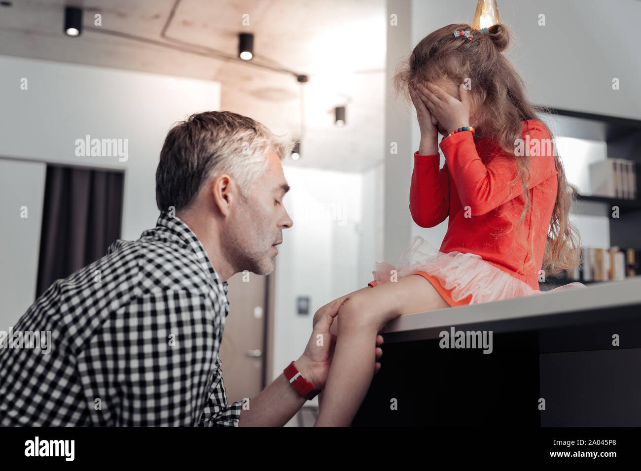 Ich bin hier. Aufmerksamen mann Blasen auf Knie, während seine Tochter unterstützen. Stockfoto