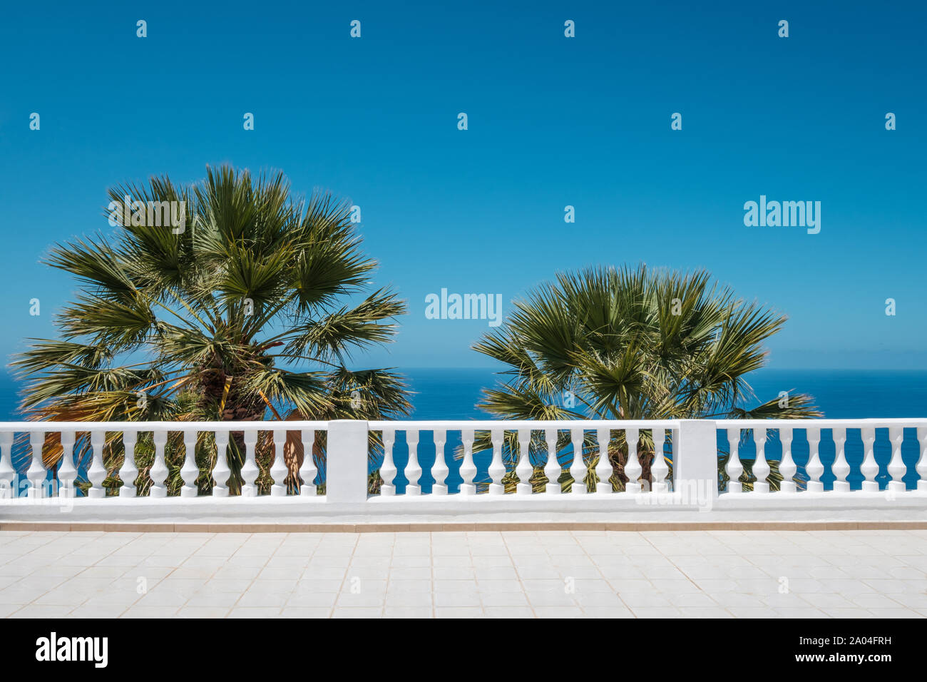 Meerblick Terrasse mit blauem Himmel und Palmen im Hintergrund Stockfoto