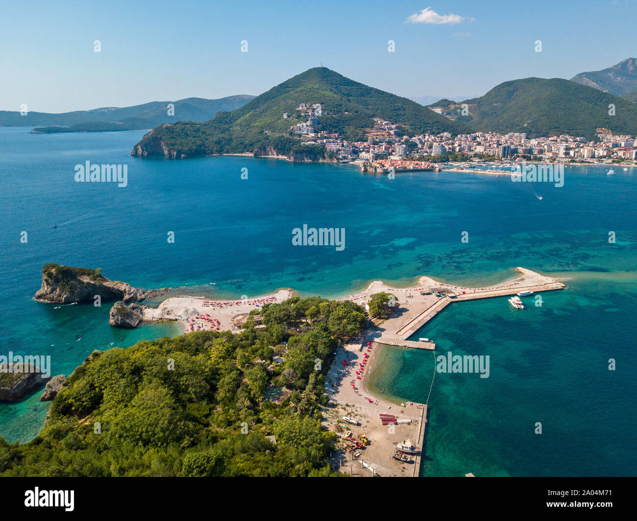 Luftaufnahme der Insel Sveti Nikola, Budva, Montenegro. Hawaii Strand, Sonnenschirme und Badegäste und kristallklarem Wasser. Zerklüftete Küsten Stockfoto