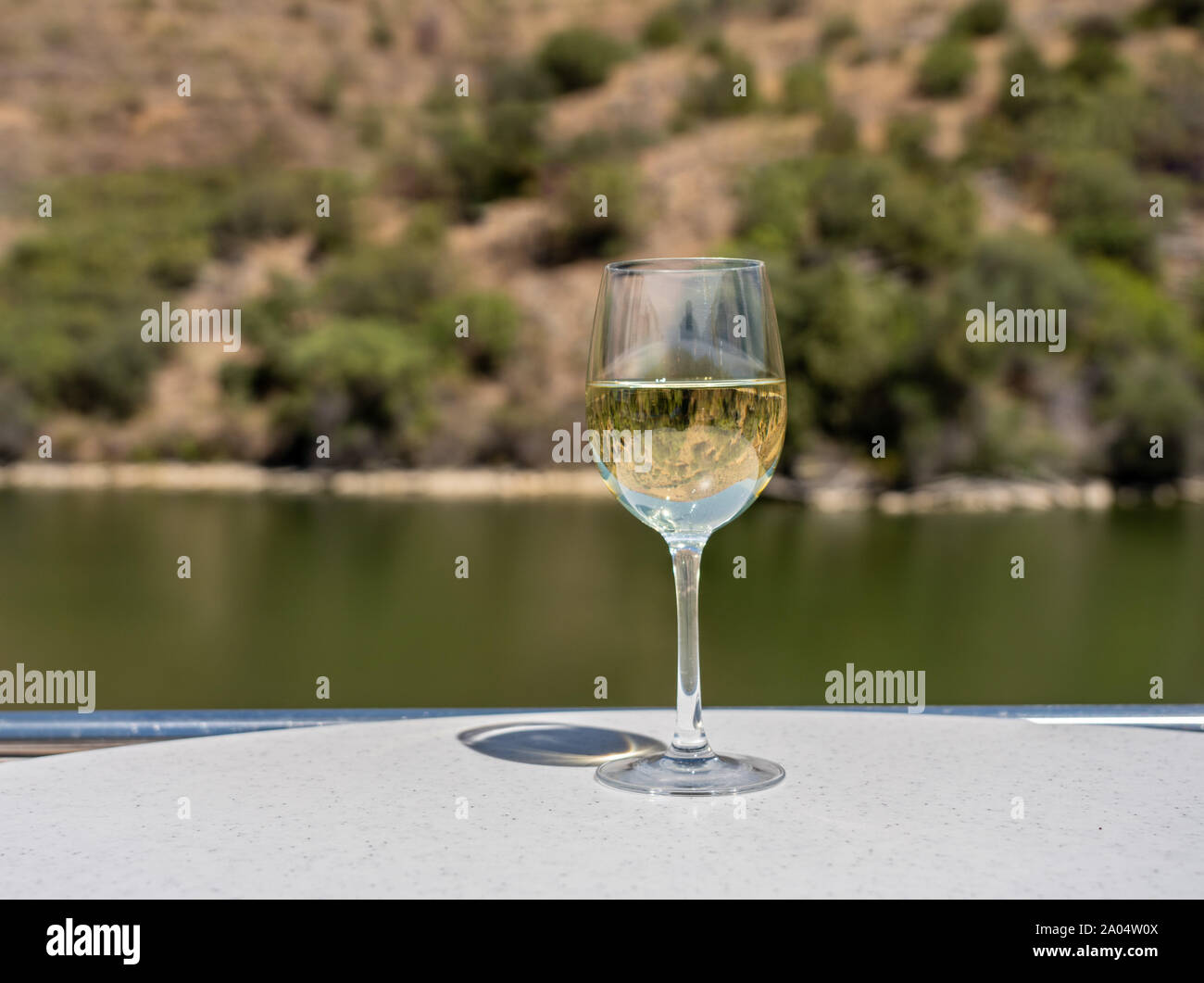 Glas Weißwein auf einer Bootsfahrt auf dem Douro in Portugal spiegelt den Fluss und die Weinberge entlang des Flusses Stockfoto