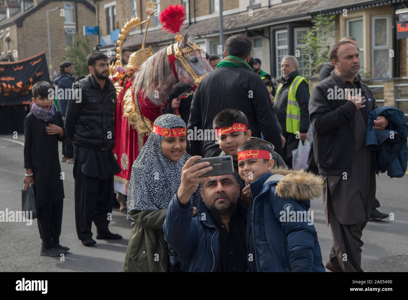 Die muslimische Gemeinde Bradford 2019 2010s UK. Tag der Ashura-Parade schiitische Muslime erinnern sich an das Martyrium von Hussain. Das Pferd repräsentiert das Pferd, das Husayn ibn Ali in die Schlacht von Karbala Vater ritt und Söhne ein Selfie mit einem iPhone HOMER SYKES machte Stockfoto